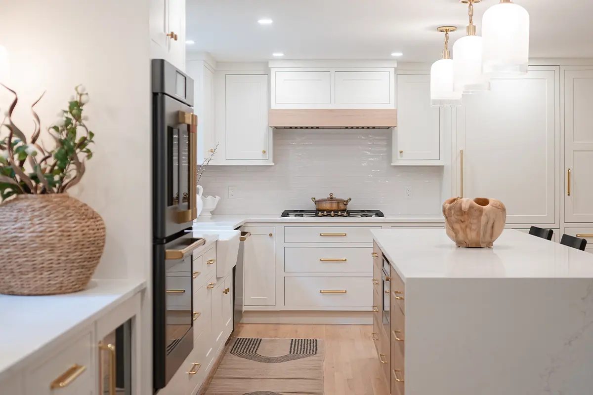 Finished white transitional kitchen with brass hardware, waterfall island, and custom hood surround