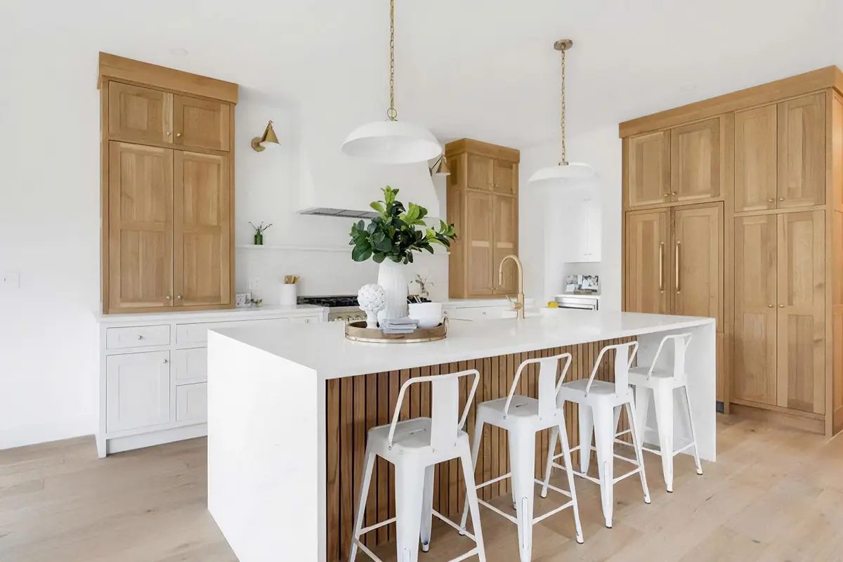 Finished white oak kitchen cabinetry with a waterfall island and integrated paneled storage