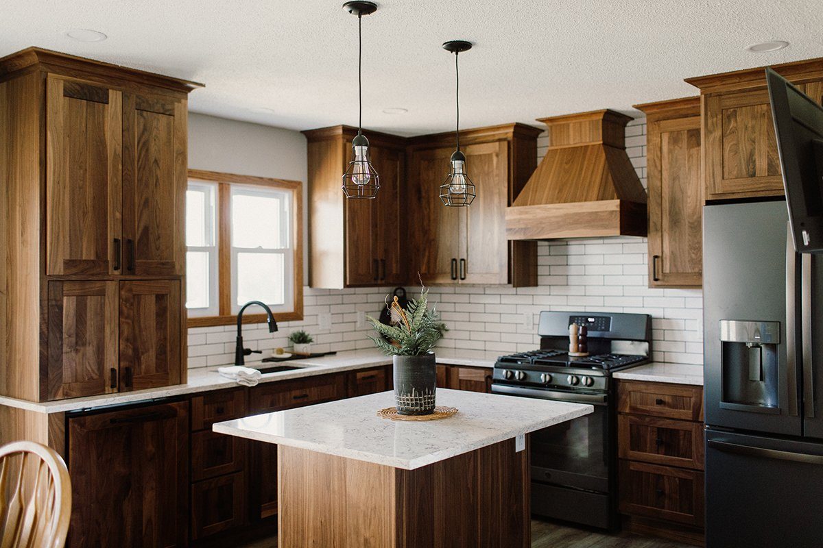 Finished walnut kitchen cabinetry with paneled storage and a custom hood surround